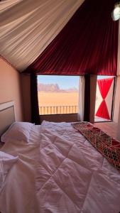 una camera da letto con un grande letto con una grande finestra di Wadi Rum Sunset Camp a Wadi Rum