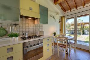 a kitchen with a stove and a table with chairs at Agriturismo Il Lentisco in Bolgheri