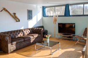 salon z brązową kanapą i telewizorem w obiekcie Loft sur l'eau en centre-ville de Compiègne w mieście Margny-lès-Compiègne