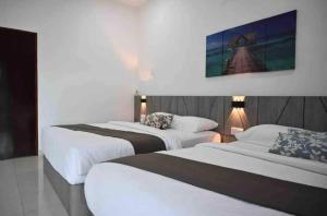una habitación de hotel con 2 camas y un cuadro en la pared en Casa Le Deer 鹿小居, en Kuah