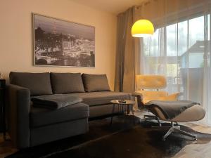 una sala de estar con un sofá y una silla en Living at Saarpartments -AdultsOnly- 2 Bedrooms, Kitchen - Business & Holiday Apartments for Long- and Short term Stay, 3 min to Train Station, Secure E-Bike Parking!, en Saarbrücken