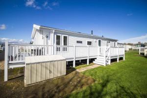 a white house with a porch and a fence at Beautiful 4 Berth Lodge With Decking At Manor Park In Hunstanton Ref 23038c in Hunstanton