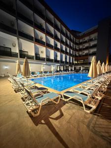 una fila de tumbonas y sombrillas en una piscina en SiDE GOLDEN ROCK HOTEL&SPA en Side