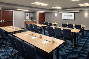 a conference room with tables and chairs and a screen at Courtyard by Marriott Portland Beaverton in Beaverton