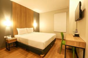 a bedroom with a bed and a desk and a television at Hotel Citradream Tugu Yogyakarta in Yogyakarta