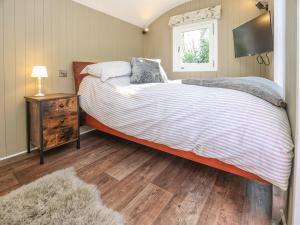 um quarto com uma cama grande e uma janela em Sybs Farm Shepherds Hut em Fernhurst