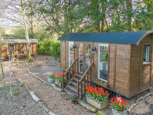 Sybs Farm Shepherds Hut في Fernhurst: كابينة خشبية مع ورود في حديقة