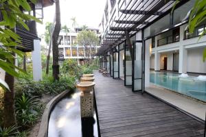 a wooden walkway next to a building with a swimming pool at Rarin Jinda Wellness Spa Resort in Chiang Mai