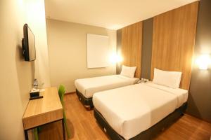 a hotel room with two beds and a television at Hotel Citradream Tugu Yogyakarta in Yogyakarta