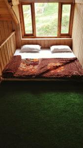 a bedroom with two beds in a room with a window at Loghouse at khajjiar lake in Khajjiar 