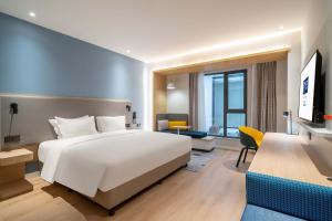 Schlafzimmer mit einem großen weißen Bett und einem Schreibtisch in der Unterkunft Holiday Inn Express Jinan Airport Zone, an IHG Hotel in Jinan