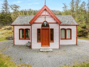 une petite maison blanche avec une porte rouge dans l'établissement Stuffers Cottage, à Inverey