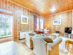 a living room with wooden walls and wooden floors at Stuffers Cottage in Inverey
