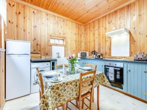 a kitchen with wooden walls and a table with chairs at Stuffers Cottage in Inverey