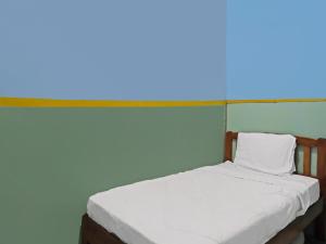 uma cama num quarto com uma parede azul em SPOT ON 92538 Joyoakis Homestay Syariah em Nagoya