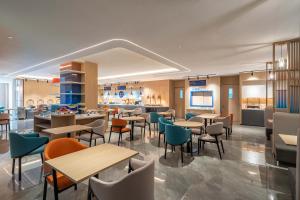 済南市にあるHoliday Inn Express Jinan Airport Zone, an IHG Hotelのテーブルと椅子のあるレストラン、キッチンが備わります。