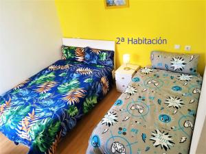 1 dormitorio con 2 camas y pared amarilla en Vivienda con 3 habitaciones PRÍNCIPE del SILENCIO, en Gijón