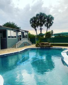 - une piscine en face d'une maison avec des palmiers dans l'établissement TETE PALM HOTEL, à Tete