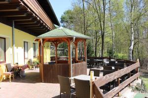 un patio con cenador, mesas y sillas en Hotel und Restaurant Karpfenschänke, en Schenkendöbern