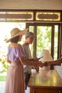 Eine Frau mit Hut und ein Mann, der ein Handy anschaut. in der Unterkunft Cabé Bali in Jasri