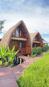 a house with a thatched roof with a walkway to it at Cabé Bali in Jasri