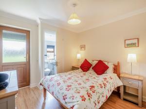 a bedroom with a bed with red pillows at Appletree Cottage in Saint Osyth