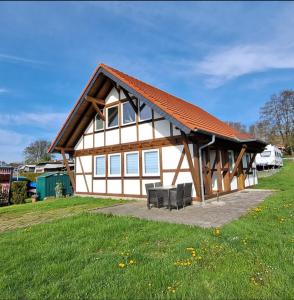 una casa con tetto rosso e due panche di HM - Ferienhaus 3 Deluxe Krombachtalsperre Westerwald exklusive verbrauchte NK a Driedorf