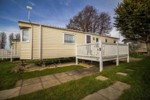 a yellow house with a porch and a white rail at Caravan With Decking At Manor Park In Hunstanton, Sleeps 6 Ref 23045b in Hunstanton