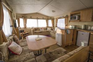 a living room with a kitchen and a table in a caravan at Caravan With Decking At Manor Park In Hunstanton, Sleeps 6 Ref 23045b in Hunstanton