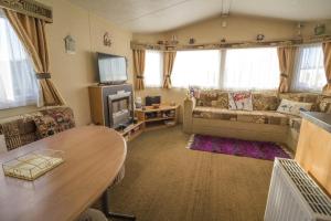 a living room with a table and a couch at Caravan With Decking At Manor Park In Hunstanton, Sleeps 6 Ref 23045b in Hunstanton