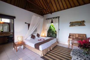 a bedroom with a bed and a television in it at Cabé Bali in Jasri +37 photos