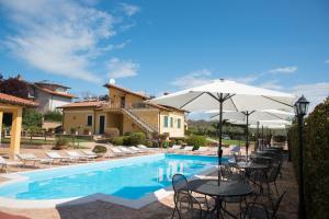 ein Pool mit Tischen und Sonnenschirmen vor einem Haus in der Unterkunft L'Infinito in Carbognano
