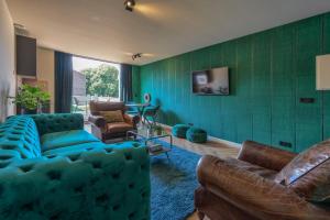 een woonkamer met een blauwe bank en een groene muur bij The Roosevelt Apartments in Middelburg