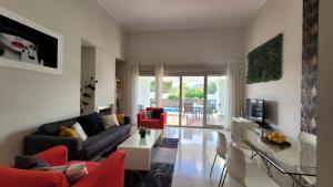 sala de estar con sofá negro y sillas rojas en Villa Golf Las Colinas, en Villacosta