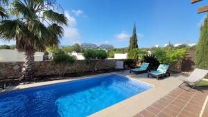 a swimming pool with two chairs and a palm tree at Villa Golf Las Colinas in Villacosta