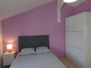 een slaapkamer met een paarse muur en een bed bij chambre privée à BORDEAUX PELLEGRIN in Bordeaux