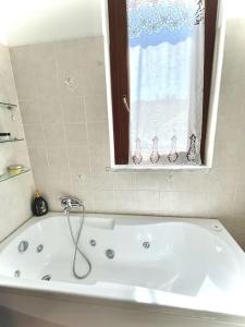 a white bath tub in a bathroom with a window at Dimora del Viaggiatore in Marina di Carrara