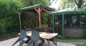 una mesa de madera y sillas con cenador en Le Gite "La cahute"-jardin en ville en Montauban