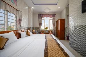 a large white bed in a room with a large window at Ris Hotel Đà Nẵng in Da Nang