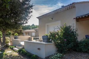 ein weißes Haus mit einer Terrasse und einem Busch in der Unterkunft Le JARDIN DES DELIS gite NEUF avec piscine bio UV in Saint-Saturnin-dʼApt