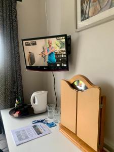 einen Schreibtisch mit einem TV an der Wand neben einem Schreibtisch mit einer Box in der Unterkunft Room with a view in Newry