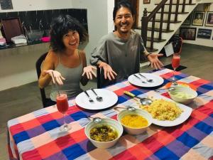 Sweet Pea Hostel في بالابيتييا: رجل وامرأة يجلسان على طاولة طعام