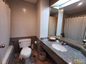 ein Badezimmer mit Toilette, Waschbecken und Spiegel in der Unterkunft Khanom Golden Beach Hotel in Khanom