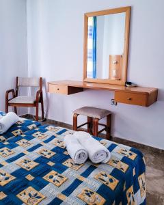 1 dormitorio con 1 cama con toallas y espejo en HOTEL ARANT en Mastichari