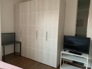 a white cabinet with a tv and a chair at A Casa di Viola - Appartamento in La Morra