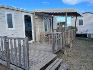 una terraza de madera con mesa y cenador en Mobil home vue mer camping Tohapi, en Vias