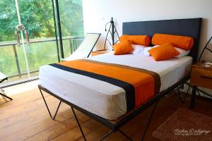 a bed with orange pillows in a room with a window at Kakulanda Resort in Kurunegala