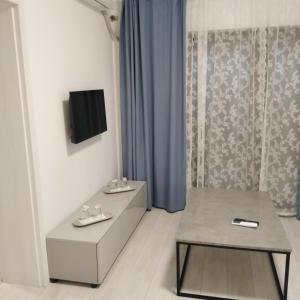 Habitación con mesa y TV en la pared. en Apartamente9- Serena de închiriat, en Băile Felix