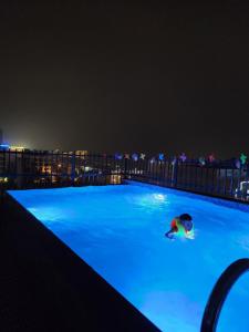 osoba pływająca w basenie w nocy w obiekcie Tuấn Đạt Luxury FLC Sầm Sơn w mieście Sam Son