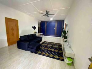 ARYAN HOMESTAY Temerloh في تيميرلوه: غرفة معيشة مع أريكة زرقاء ومروحة سقف